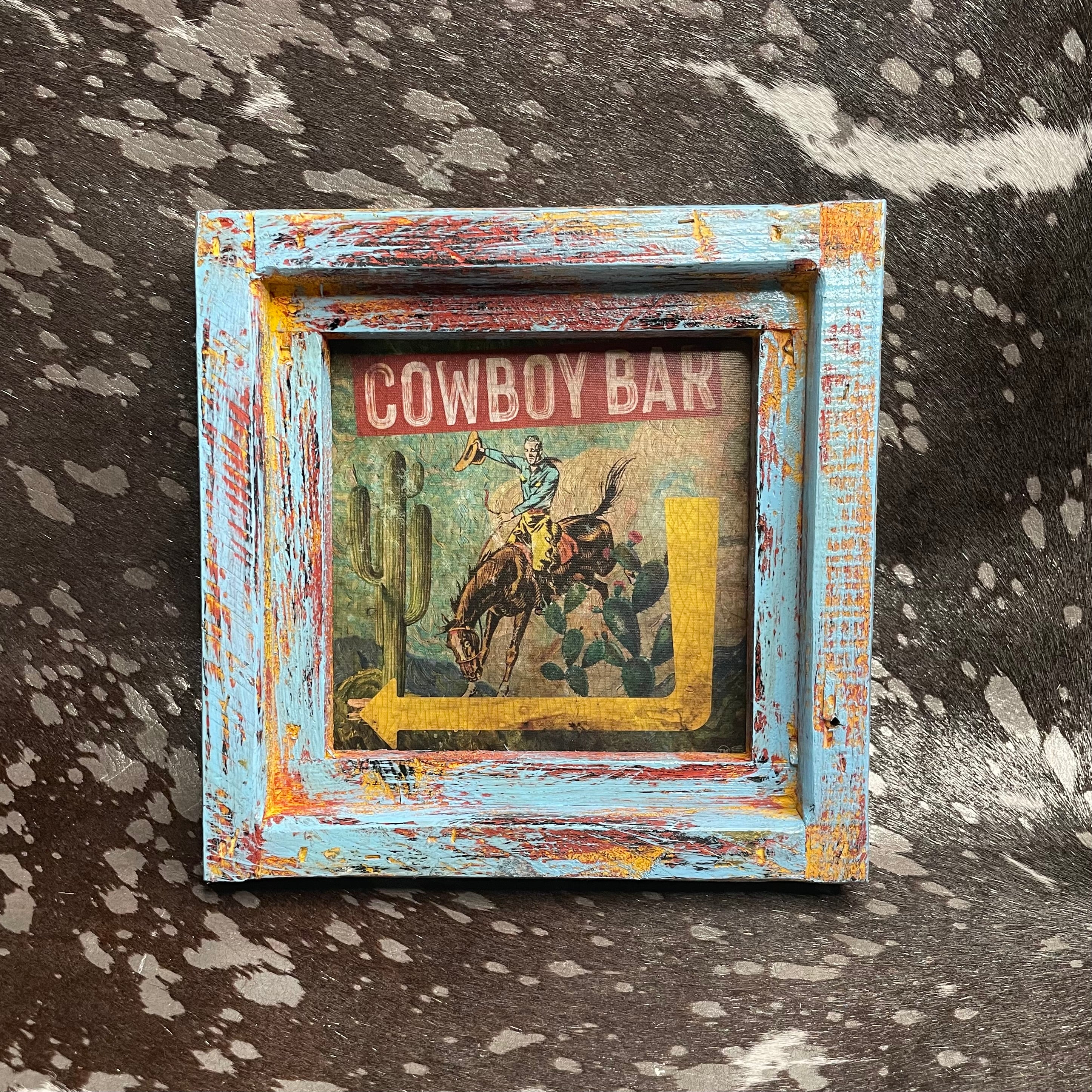 Framed cowboy bar sign with distressed frame on a textured surface