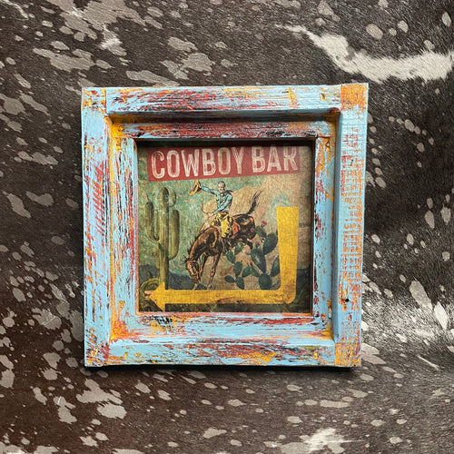 Framed cowboy bar sign with distressed frame on a textured surface