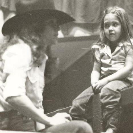 Black and white photo of a woman and a child sitting together at a rodeo.